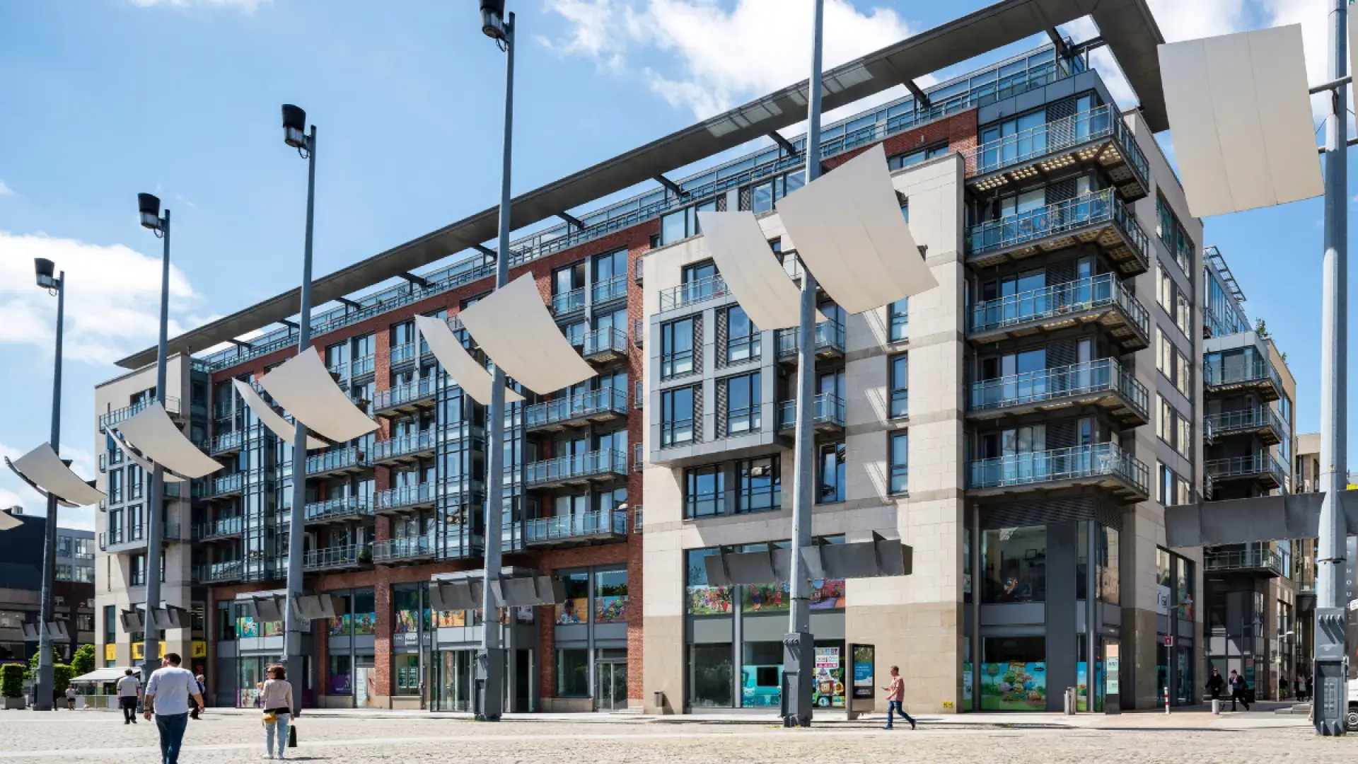 Modern multi-story building exterior with glass balconies and street view.
