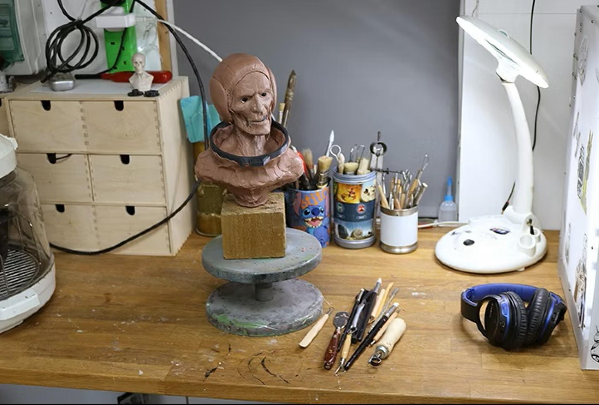 Sculpting workstation with clay bust on a turntable and tools organized nearby.