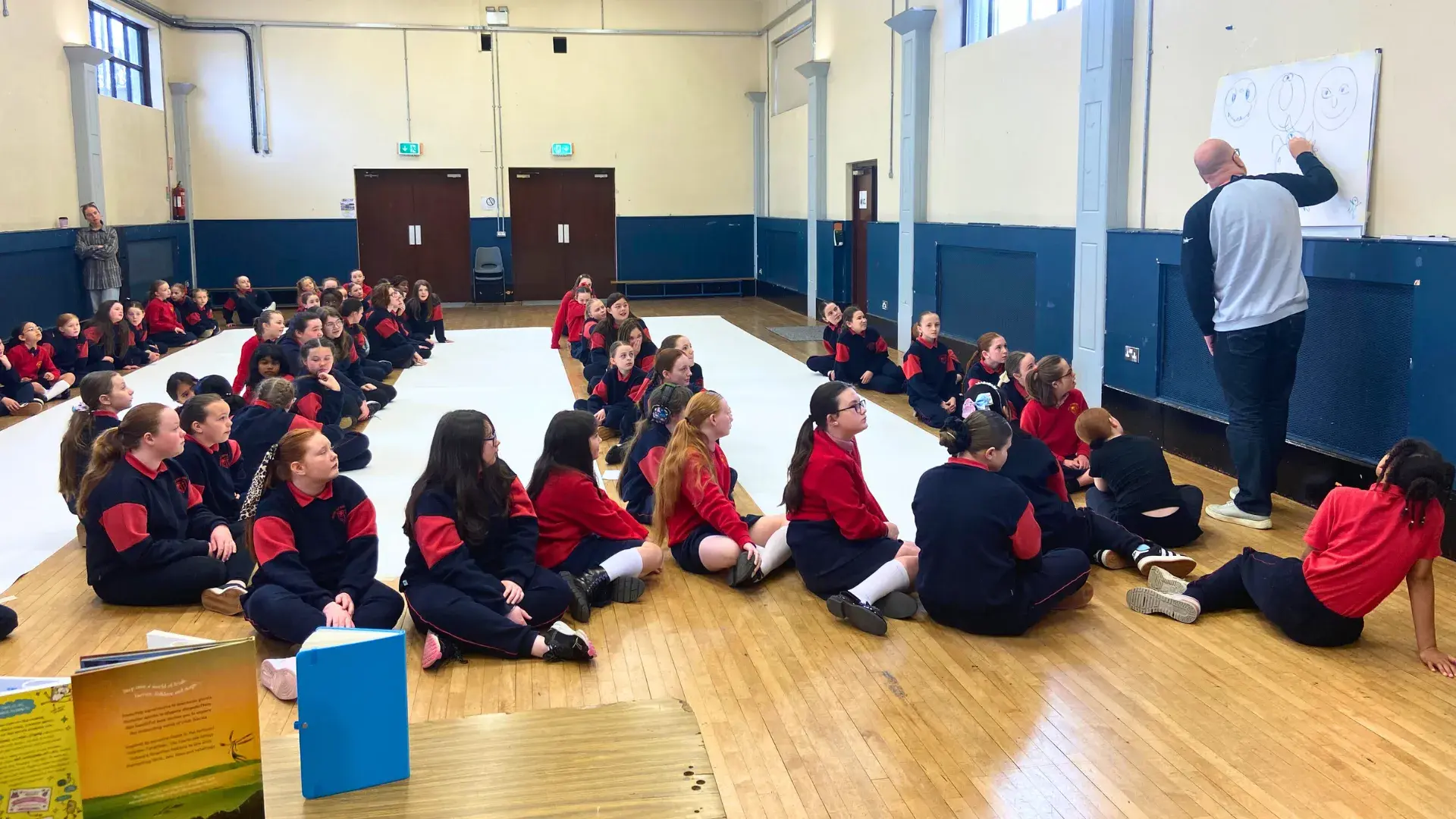 Children drawing a large monster doodle in their school gym