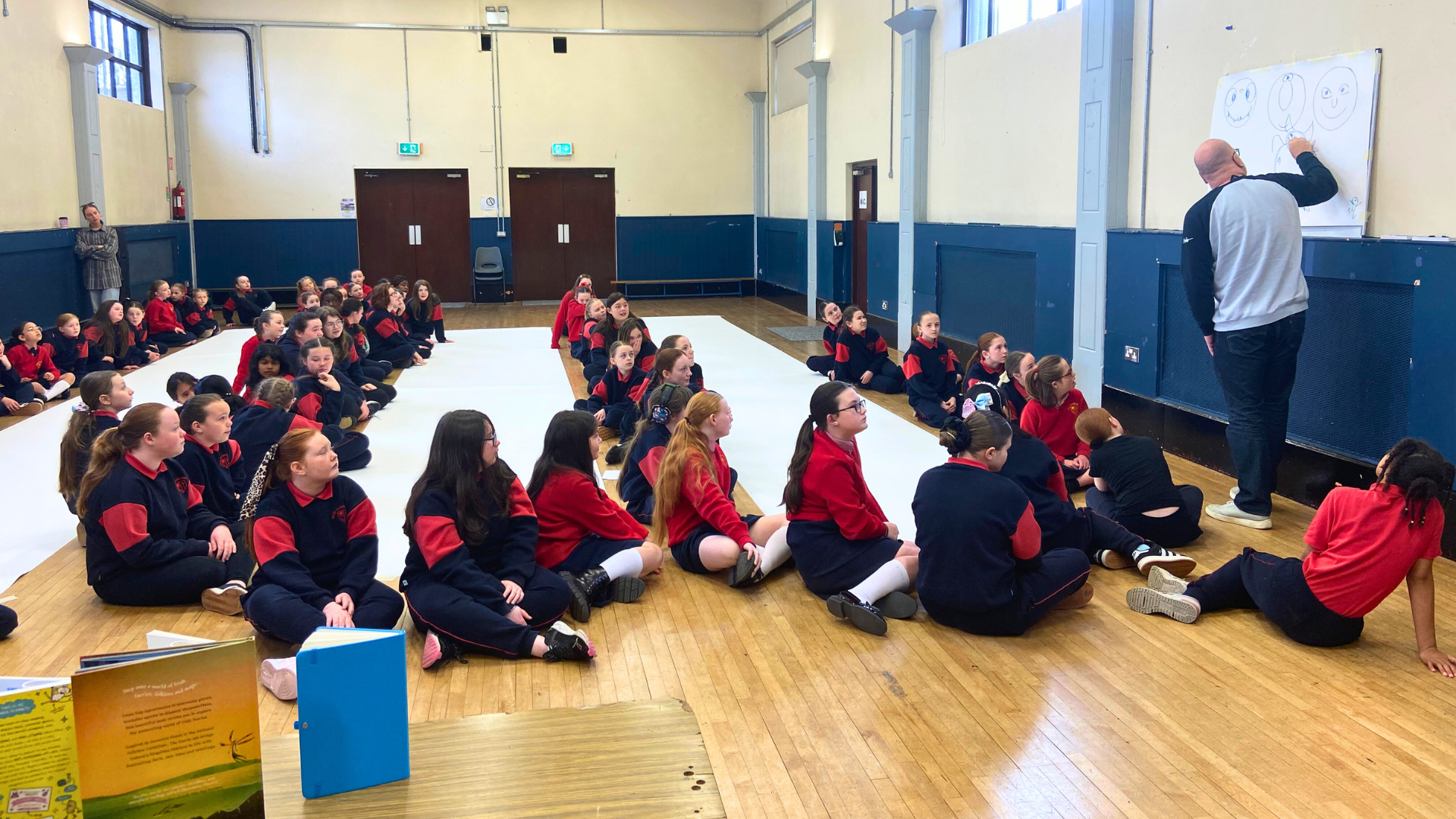 Children drawing a large monster doodle in their school gym