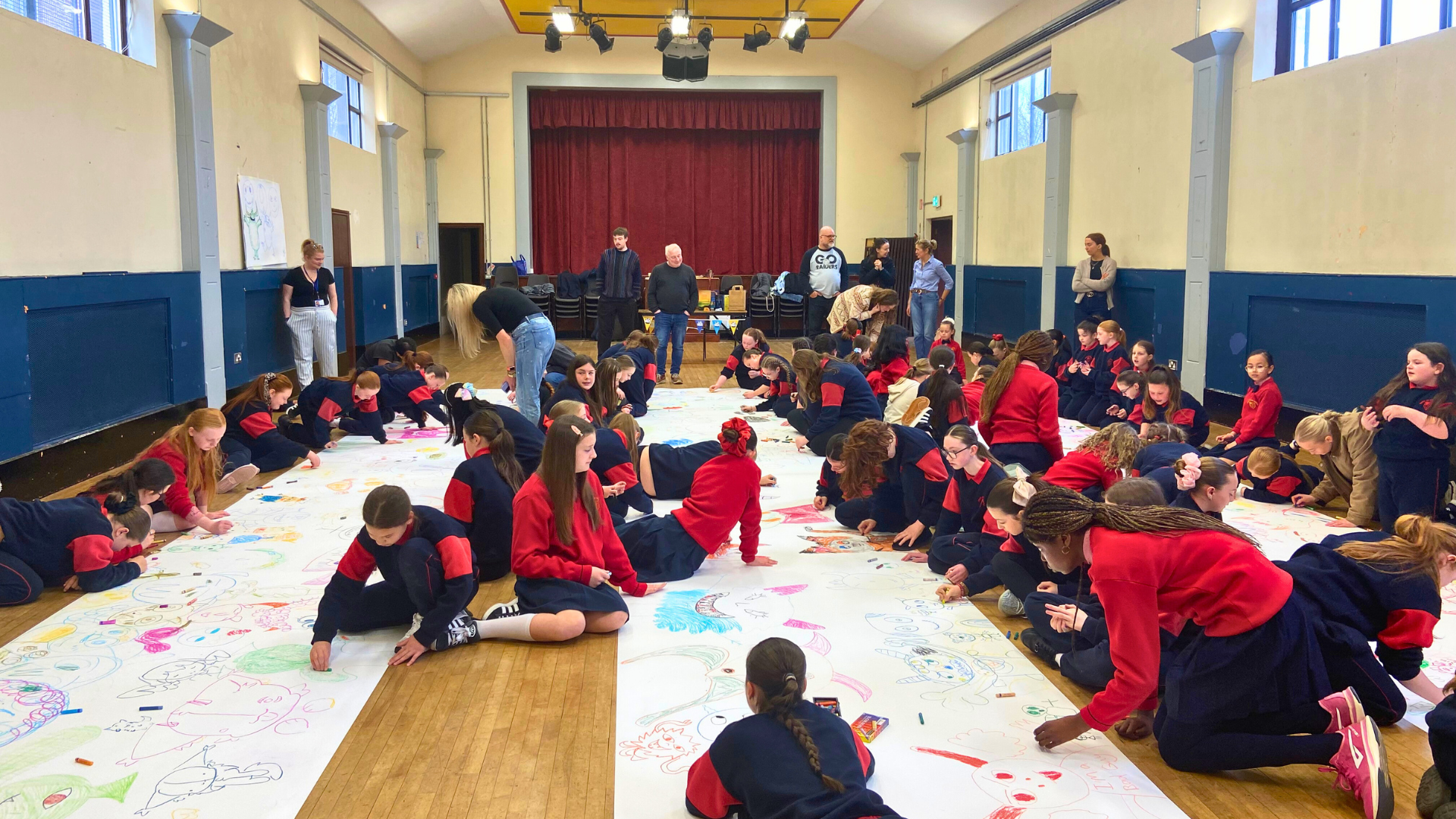 Children drawing a large monster doodle in their school gym