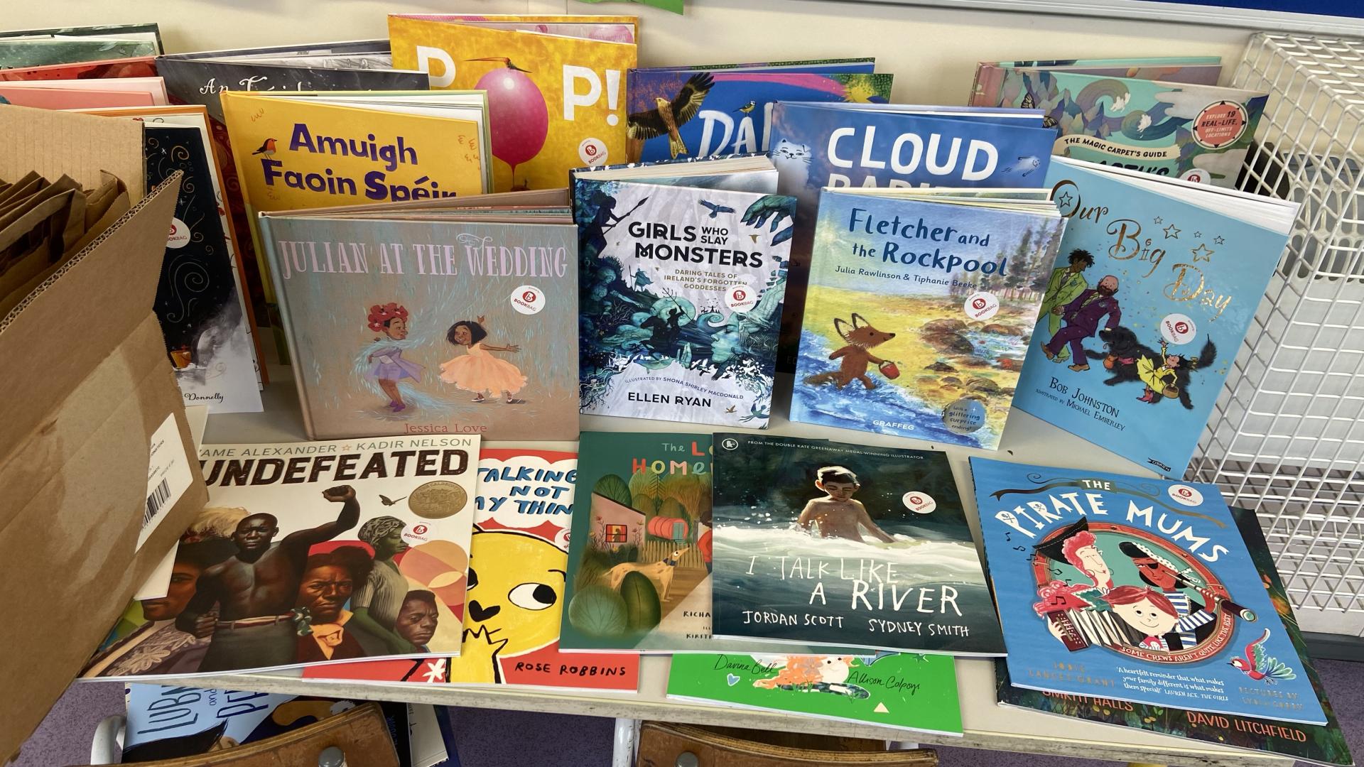 Table stacked with picture books featuring diverse titles and illustrations.