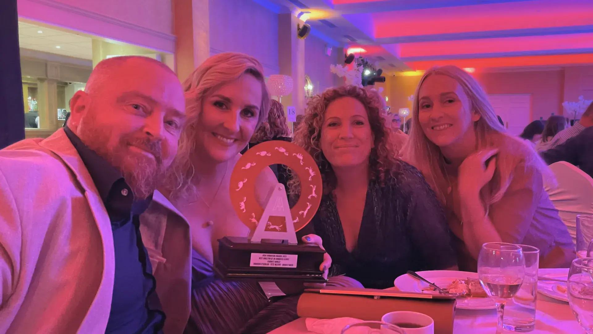 Group seated at a table with Irish Animation Award trophy displayed in the center.