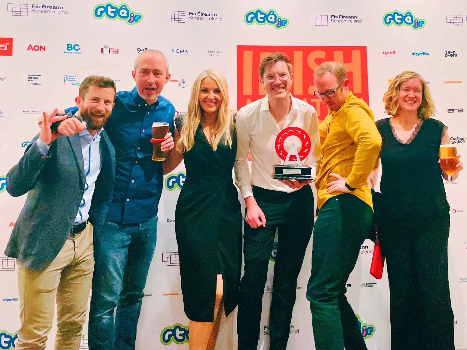 Group standing in front of Irish Animation Awards backdrop, one person holding trophy.
