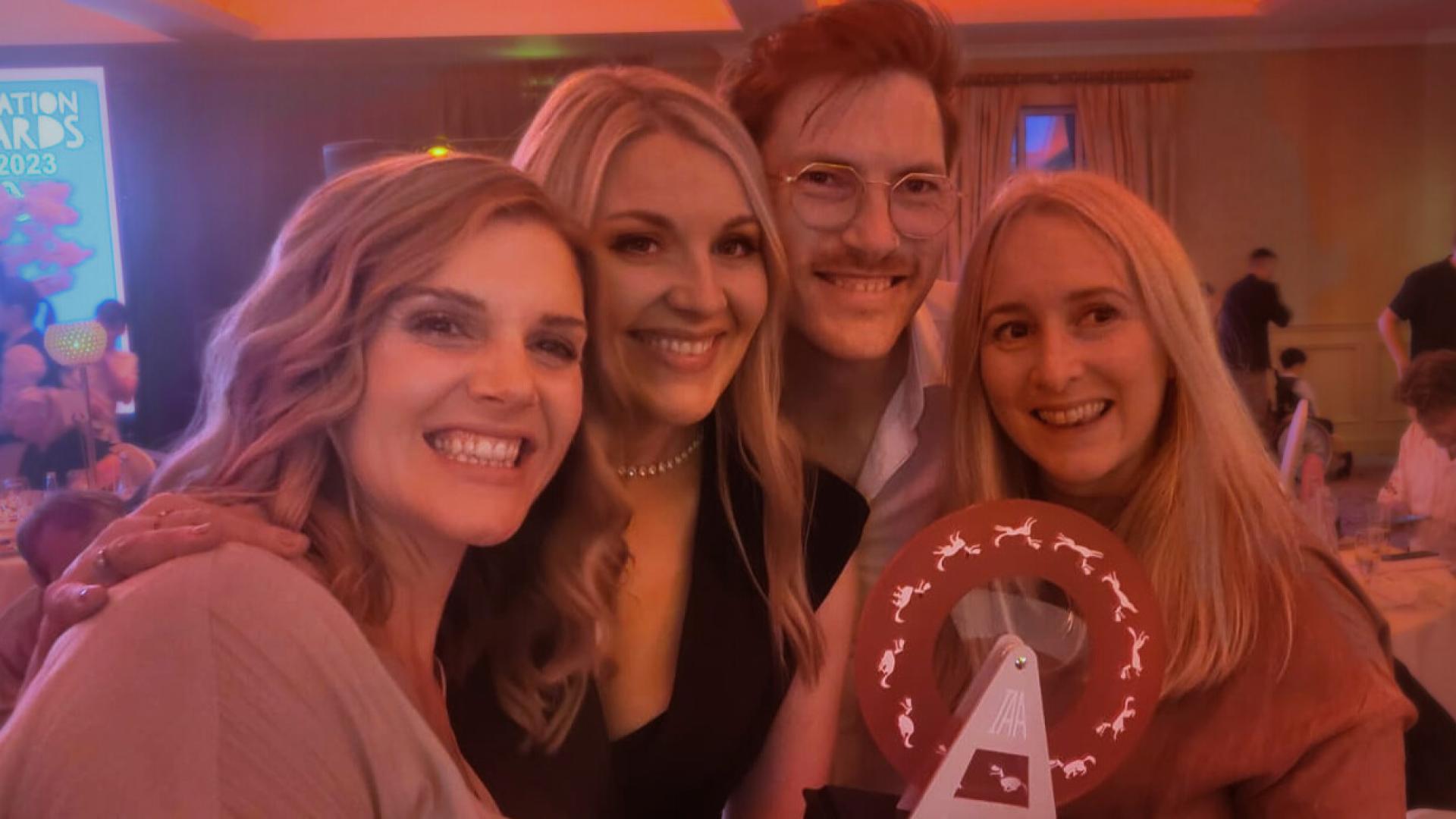 Group posing at a table with Irish Animation Award trophy visible in front.