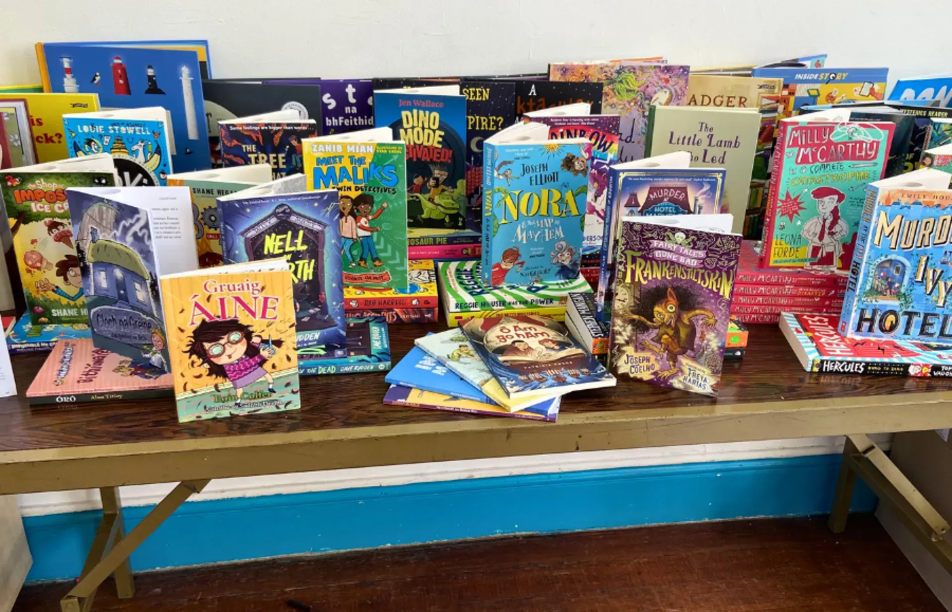 A wide selection of children’s books arranged across a long wooden table, showing various illustrated covers and reading levels.
