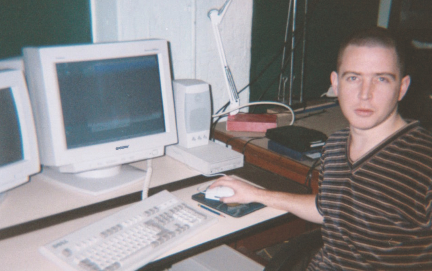 Person seated at a desk using a computer with two CRT monitors and a keyboard.
