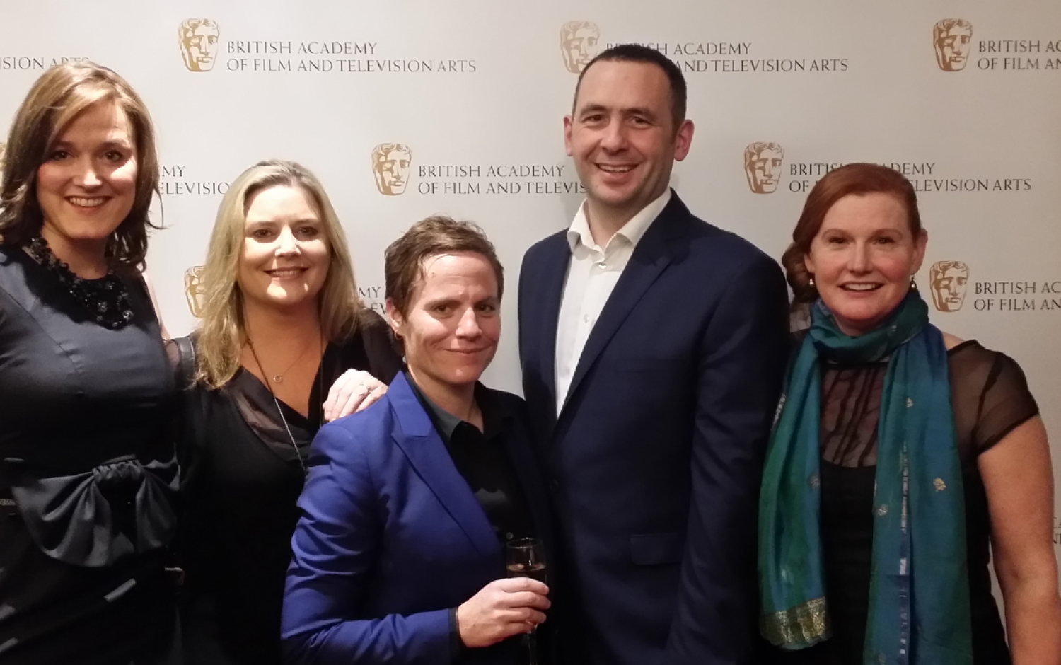Group posing in front of a BAFTA-branded backdrop at a formal event.