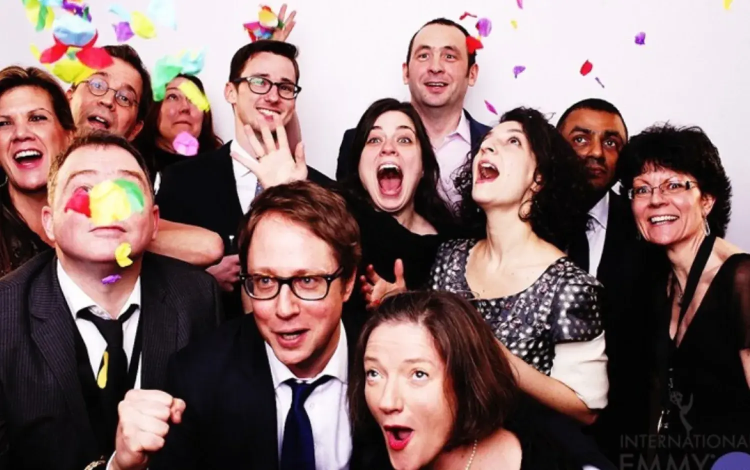 Group photo at an International Emmy Kids Awards event, with people dressed in formal attire standing close together, with colorful confetti falling around the people.