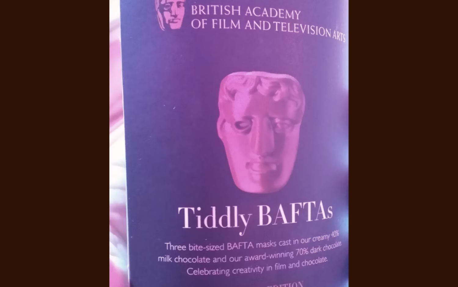 Close-up of a purple BAFTA-themed chocolate box labeled “Tiddly BAFTAs,” featuring a molded BAFTA mask design.