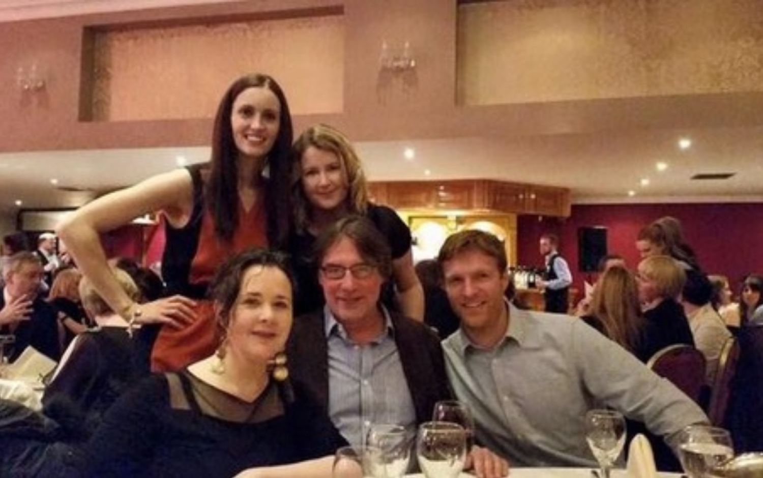 Group photo at a banquet table during an event with wine glasses and table settings.