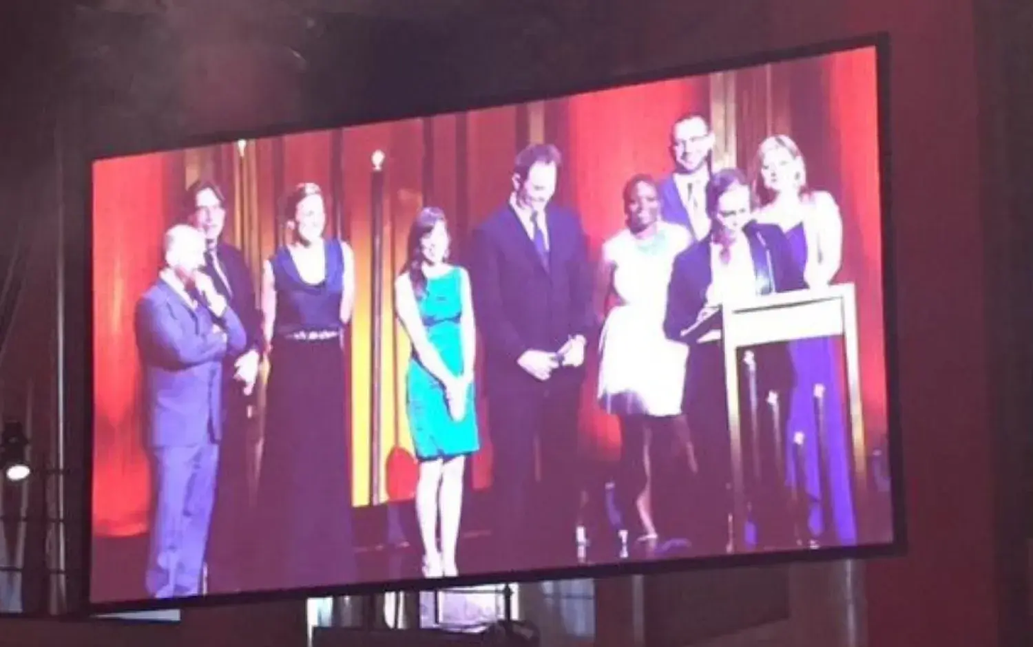 Large screen showing a group on stage during an awards ceremony.