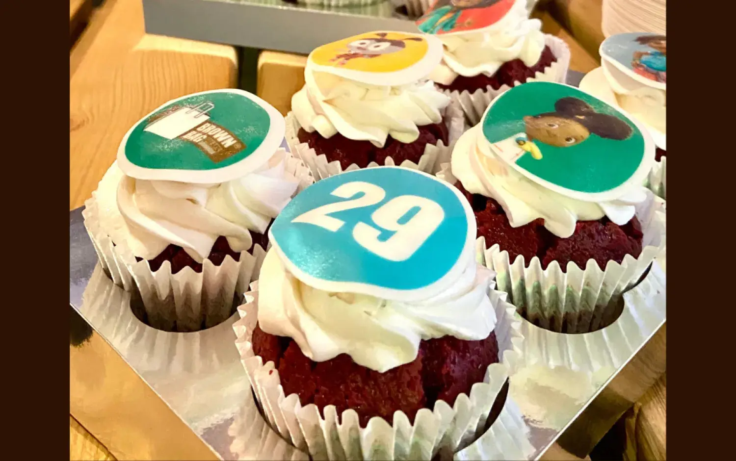 Cupcakes with white frosting and edible toppers featuring animated characters and the number 29.
