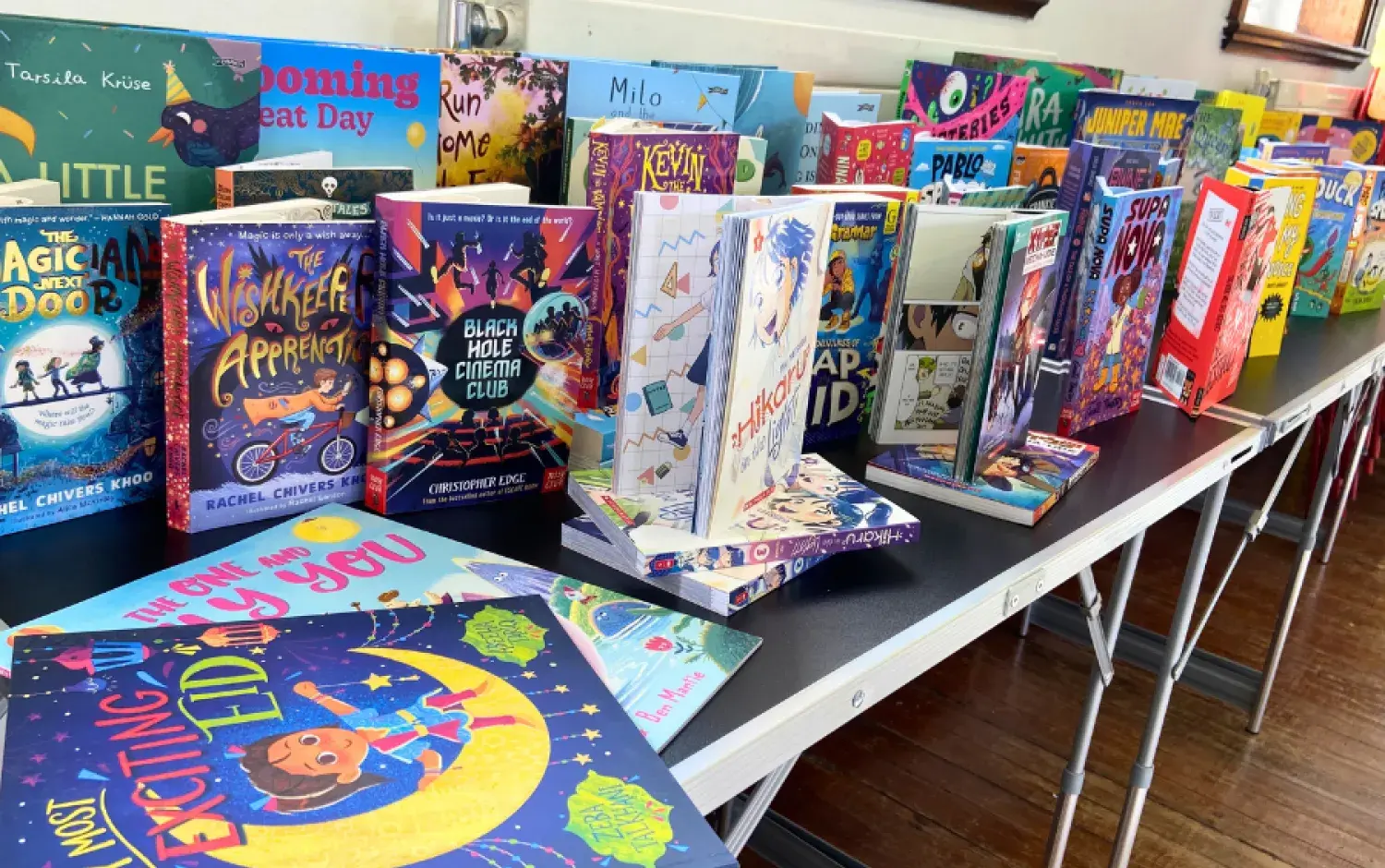 Close‑up view of children’s books standing on a table, showing colourful spines and illustrated front covers.