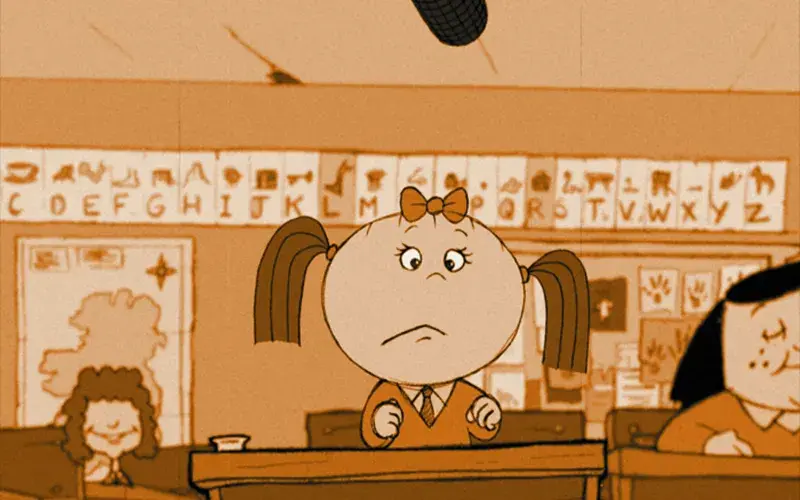 A classroom scene with a young student sitting at a desk looking up at a microphone hanging from the ceiling. Other students are visible in the background.