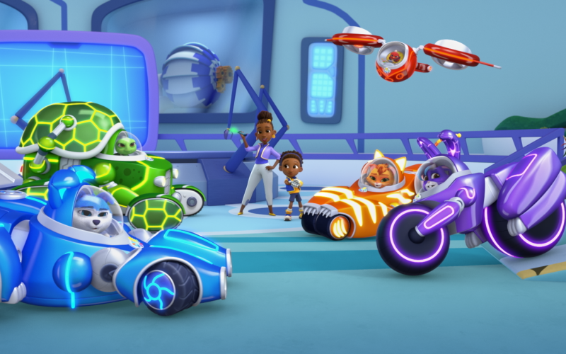 Colorful animated scene from RoboGobo showing a futuristic lab or garage where animal heroes gather with their high‑tech vehicles: a blue race car with glowing accents, a green turtle‑themed vehicle, an orange striped car, a sleek purple motorcycle, and a red flying vehicle.