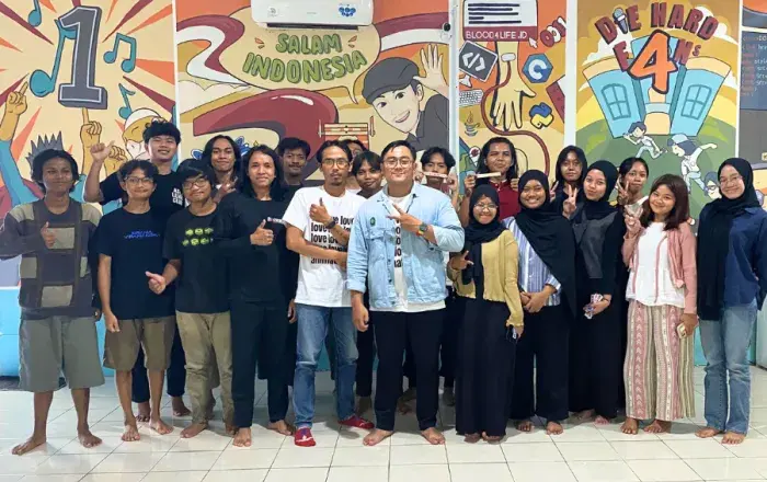 Large group posing indoors in front of colorful mural wall with illustrated graphics and text.