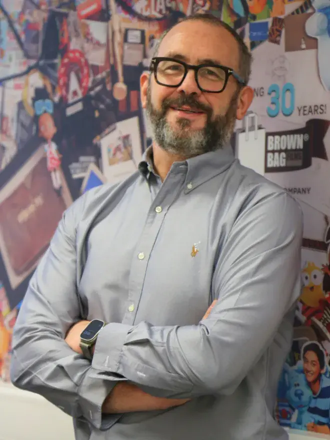A portrait photo of Cathal Gaffney, with a colourful wall behind him.