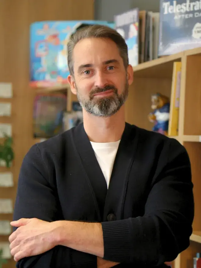 A portrait photo of James Stacey, bookshelves in the background