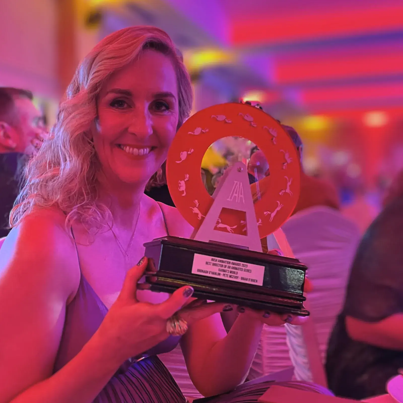 Person holding Irish Animation Award trophy with red circular design and engraved plaque.