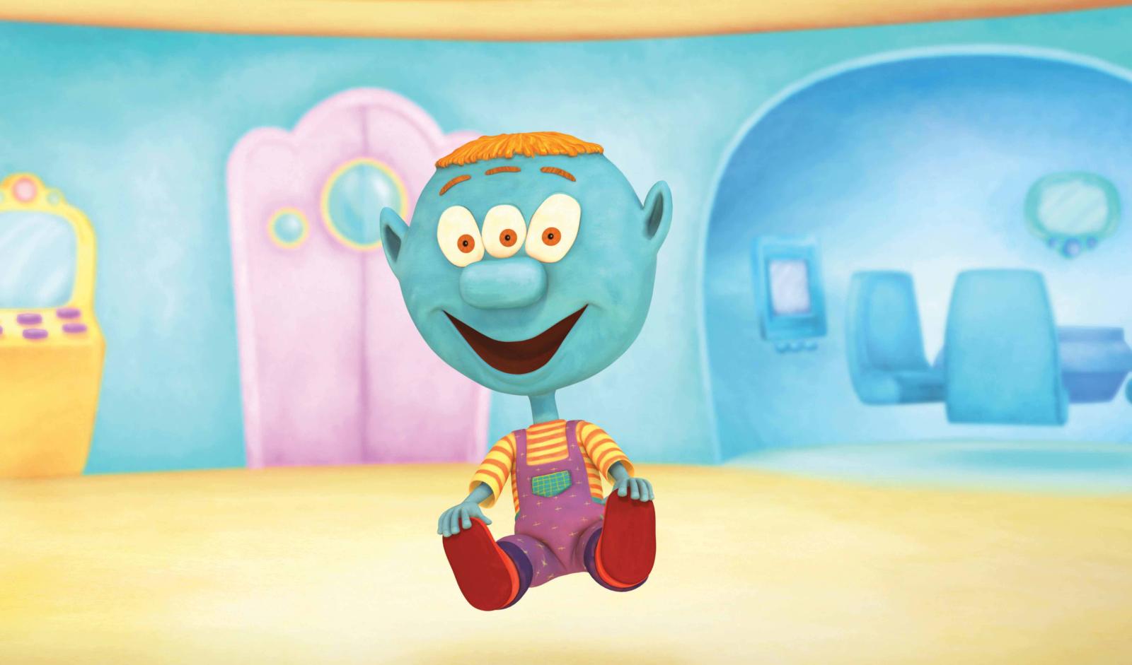 Blue three-eyed animated character sitting on the floor in a bright, colorful indoor space with curved walls and furniture.