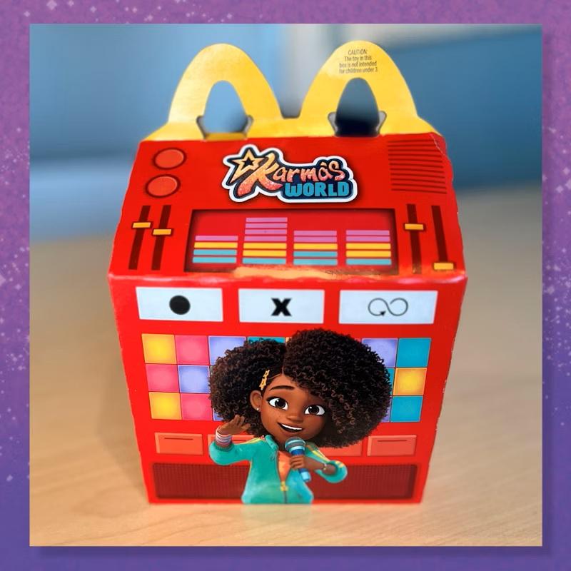 Close-up of Karma’s World Happy Meal box featuring bright red design with logo and colorful patterns.