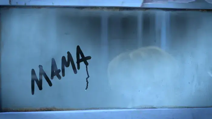 A still from the short film Anya featuring a young orphan girl on a train with the word mama scrawled on the steamed up window