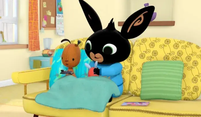 Bing and Flop under a blue blanket on the couch