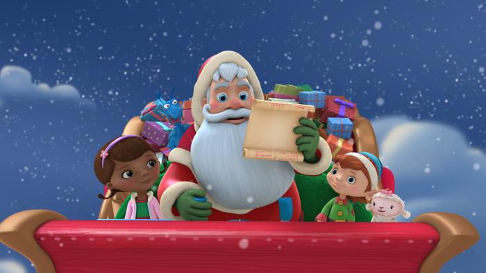 Doc McStuffins sitting next to Santa Claus in his sleigh as it flys through the night sky. Santa is holding an opened scroll in his hand.