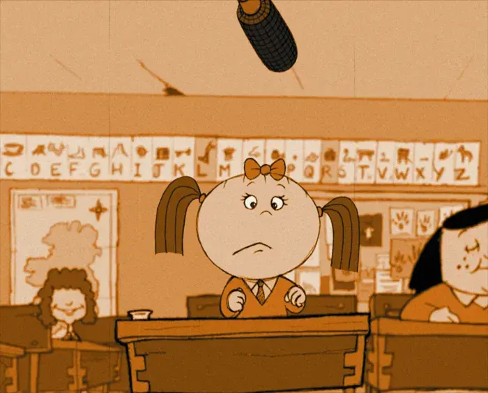 A classroom scene with a young student sitting at a desk looking up at a microphone hanging from the ceiling. Other students are visible in the background.