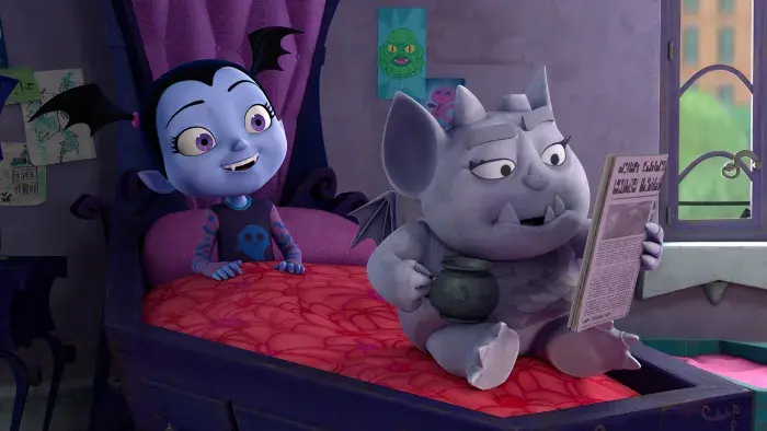 Vampirina and Gregoria sitting on top of Vampirina's bed. Gregoria is reading a newspaper.