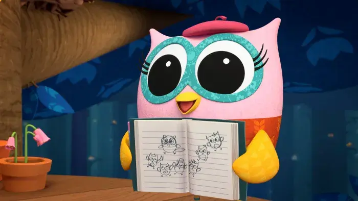 Pink owl holding a notebook with sketches.