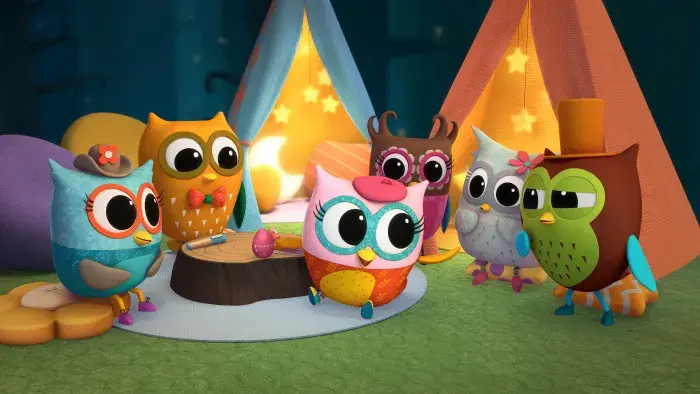 Group of owlets huddled together near some colourful tents.
