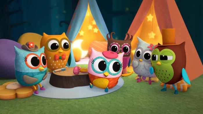 Group of owlets huddled together near some colourful tents.