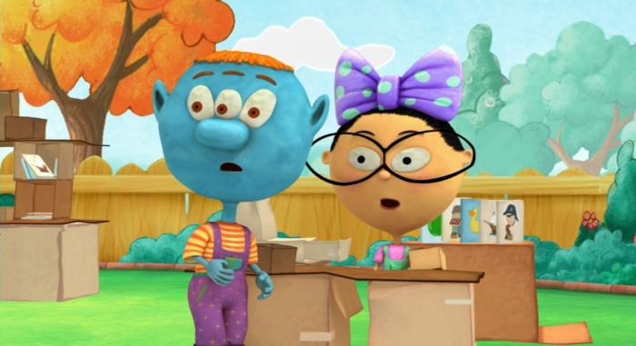 Two animated characters surrounded by cardboard boxes in a grassy yard, appearing to work on a creative project.